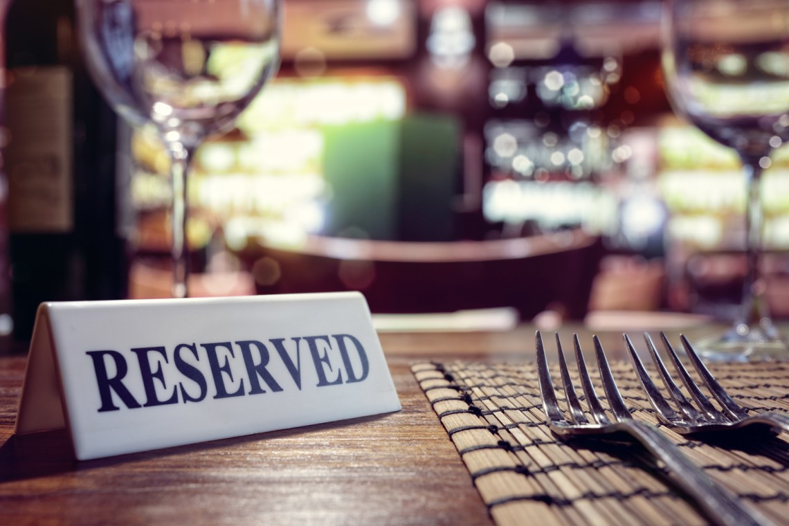 Reserved sign on restaurant table with bar background